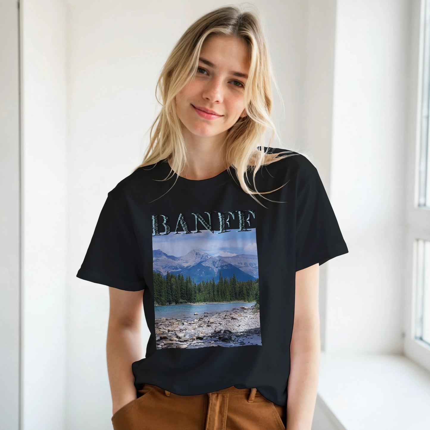 Person wearing a black t-shirt with a scenic design and 'Banff' text. Banff plus size Classic Unisex Crewneck T-shirt | Gildan® 64000